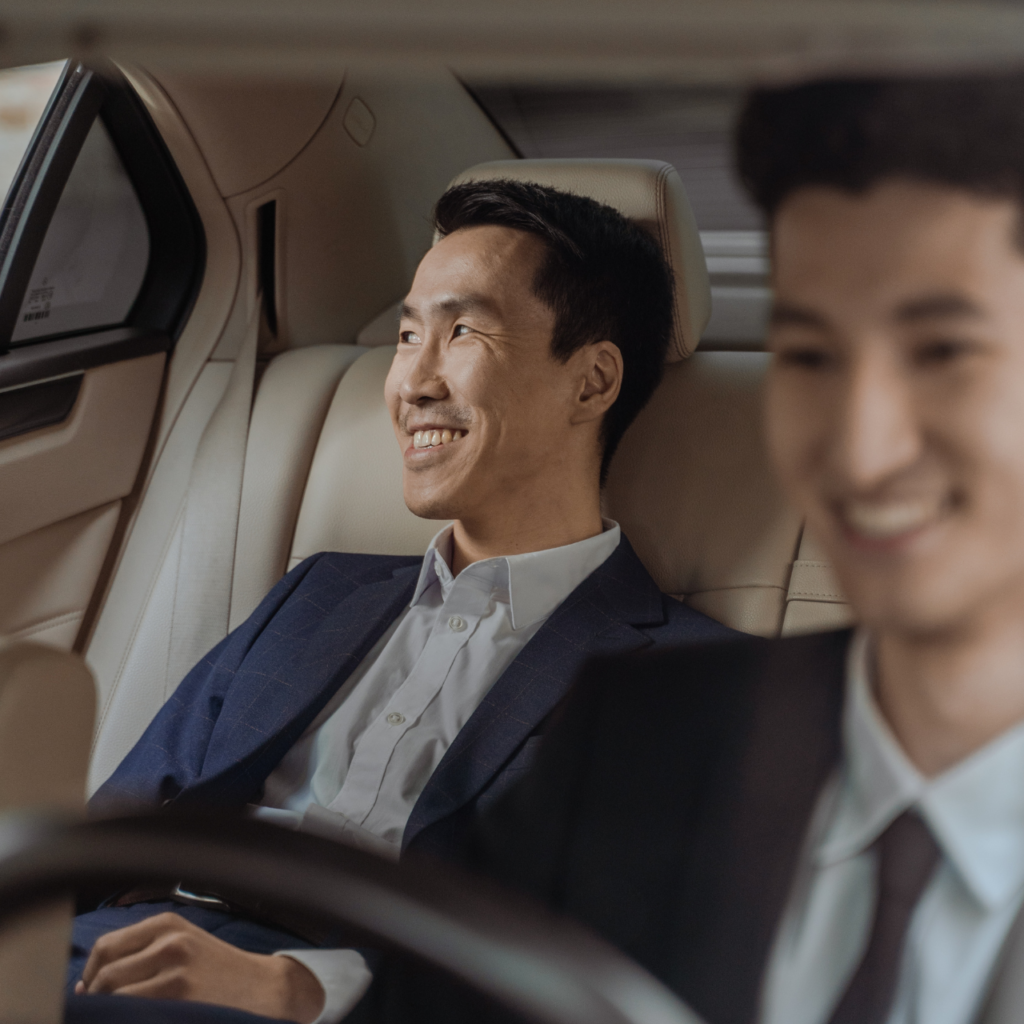 Two business passengers smiling in the back of a chauffeur-driven car